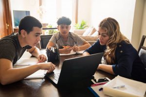 Mother homeschooling two children via laptop computer