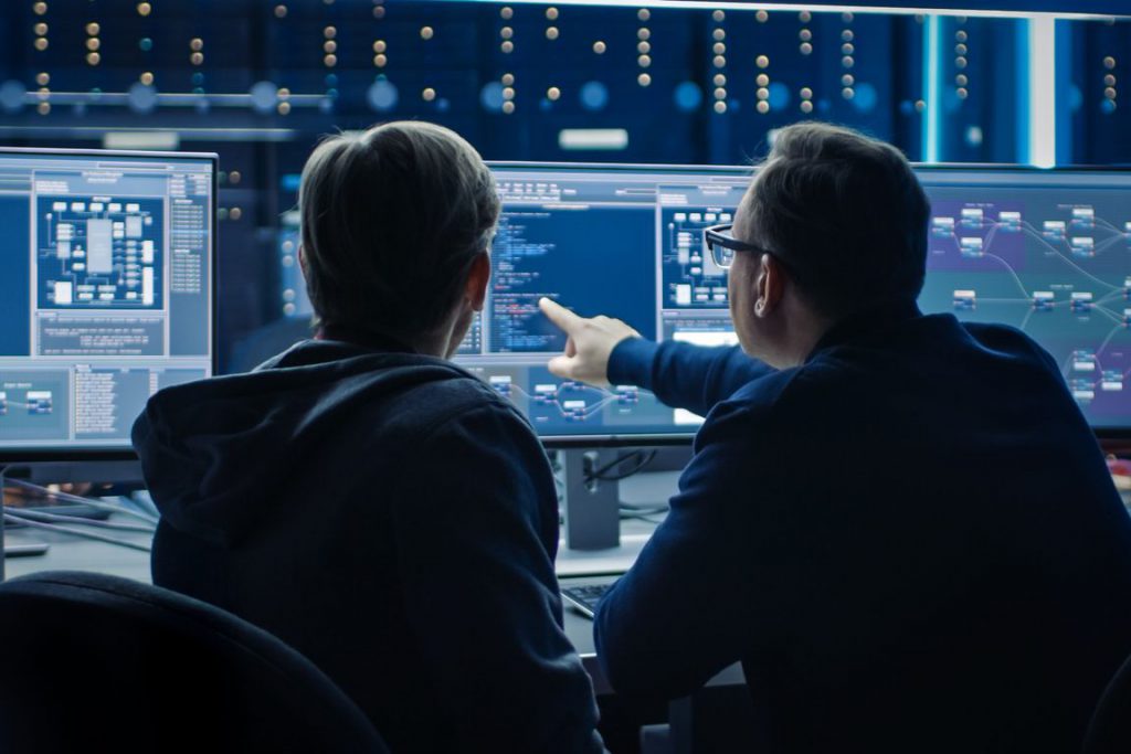 Two IT security professionals looking at code and discussing data security