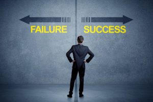Person standing in front of two arrows pointing. One point to success, the other failure