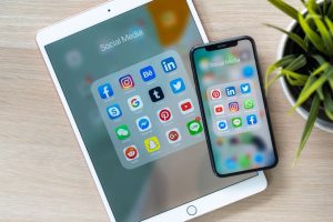 Social media icons shown in the screen of iPhone X and ipad pro; right social media channel for business concept
